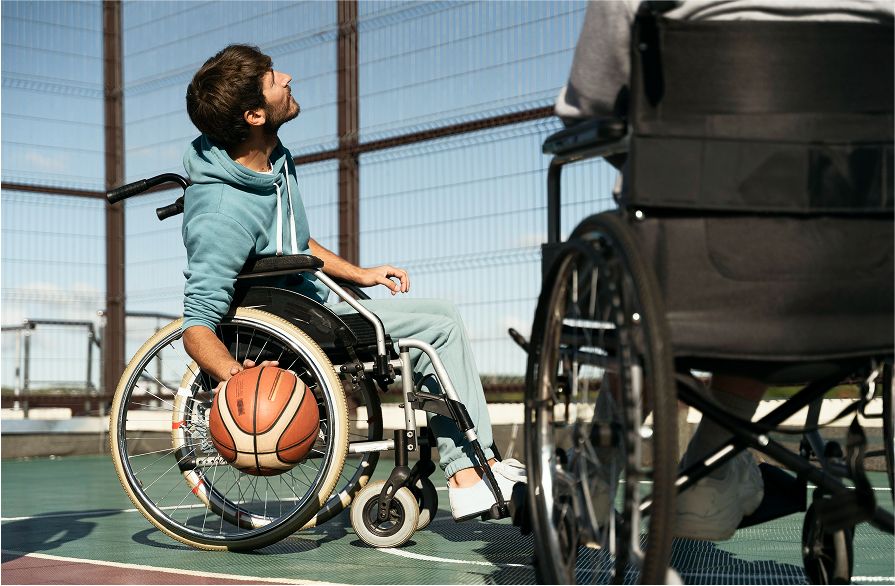 Two people playing wheelchair basketball on a sunny outdoor court