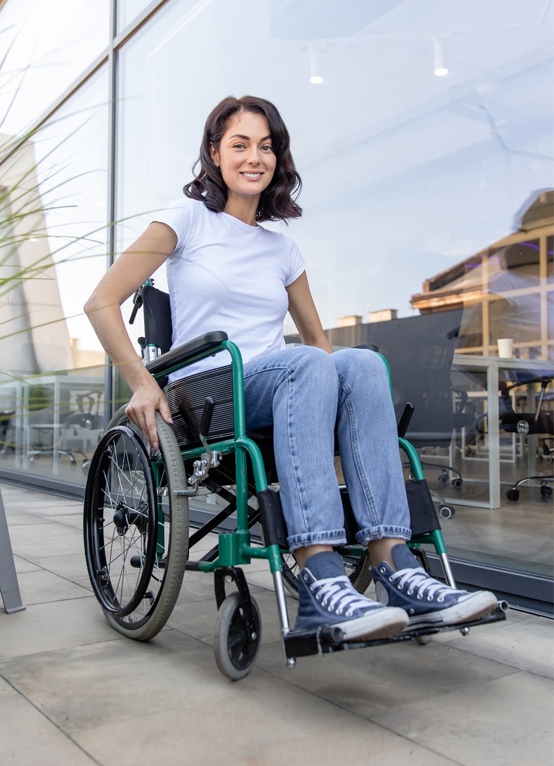 A smiling woman in a wheelchair outside a modern office building